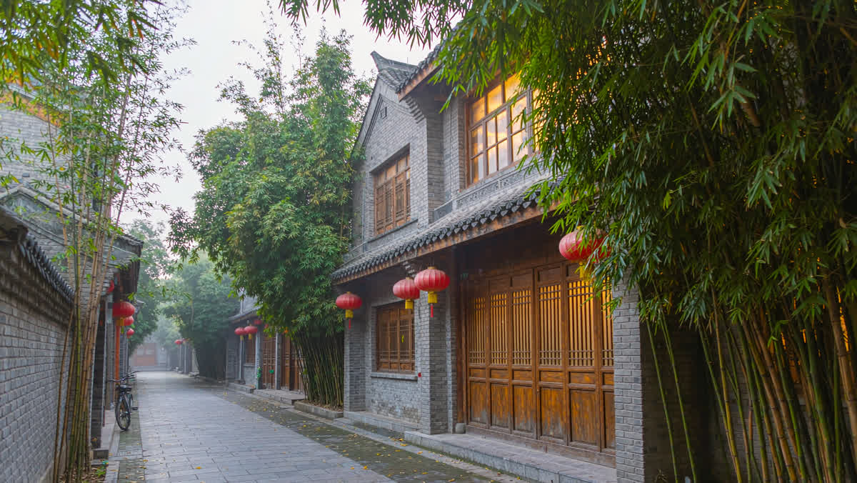 A quiet old street in Chengdu at dusk with red lanterns, bamboo and a teahouse with glowing windows