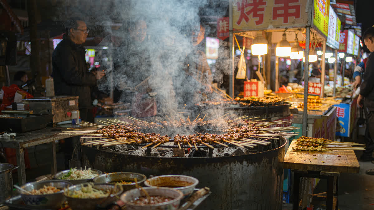 Skewers sizzling over a charcoal grill at a Chinese night market stall