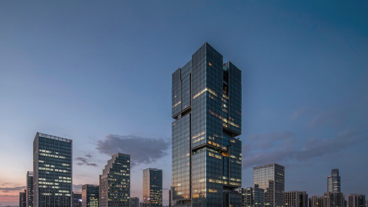 A view from a rooftop terrace overlooking a modern Chinese city skyline of glass towers at blue hour.
