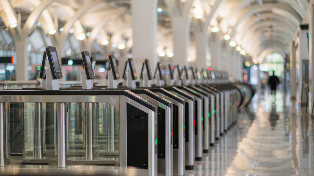 A row of modern automatic ticket turnstiles in a bright Chinese high-speed rail station with a marble floor.
