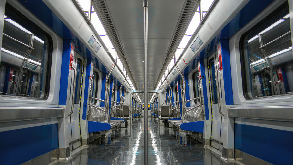 The interior of a modern empty Chinese metro carriage with rows of seats, seen down the aisle.
