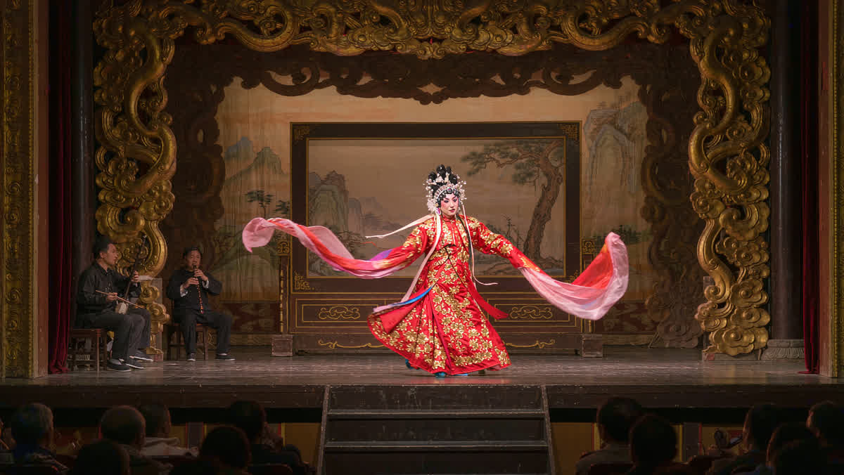 A Peking opera performer in embroidered costume with painted face on a Beijing theatre stage