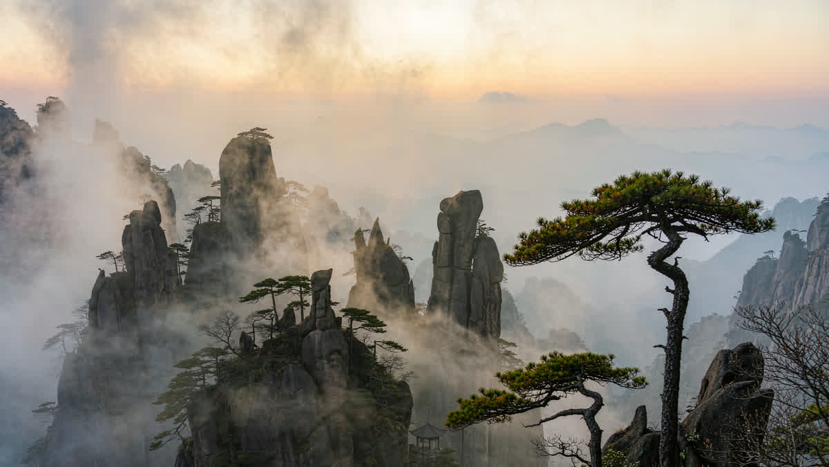 A mountain landscape with granite peaks, twisted pines and a stone pavilion in drifting mist